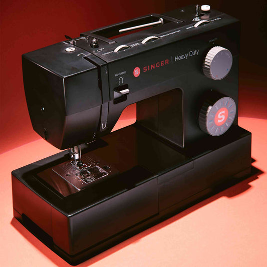 Singer 4432 sewing machine in black shown with red background  on front side angle